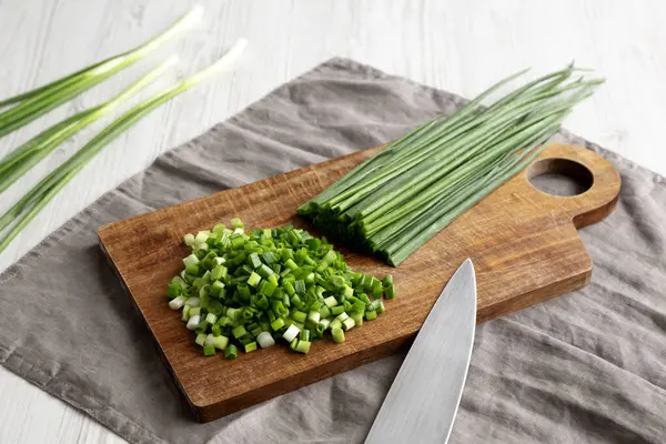 Tahta üzerinde organik kesilmiş yeşil soğan soğanı, yan görüş..
