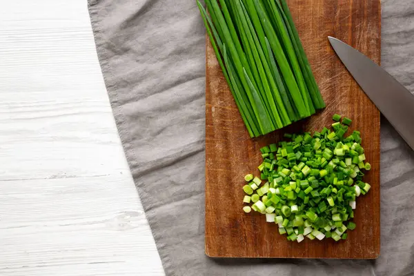 Tahta üzerinde organik kesilmiş yeşil soğan soğanı, üst manzara. Boşluğu kopyala.
