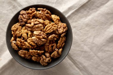 Bir kasede çiğ ceviz yarımları, üst manzara. Dümdüz, tepede. Boşluğu kopyala.