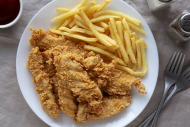 Tabakta patates kızartması olan ev yapımı tavuk şeritleri.. 