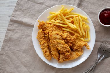 Tabakta patates kızartması olan ev yapımı tavuk şeritleri.. 