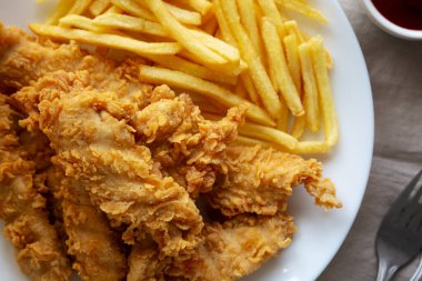 Tabakta patates kızartması olan ev yapımı tavuk şeritleri.. 