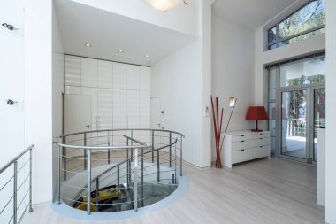 Lüks özel evdeki modern salon. Cam ve metalden yapılmış spiral merdiven. Beyaz dolap.