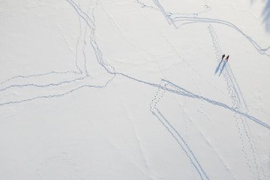 Karda ayak izleri var. Üst dron görüntüsü. Kış doğası. Kayak yapan insanlar.