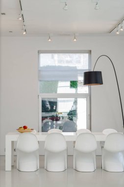 Lüks özel evin modern iç mimarisi. Yemek masası ve sandalyeleri olan geniş bir oturma odası. Beyaz duvarlar.