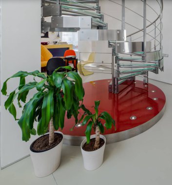 Lüks özel evde metal ve camdan yapılmış spiral merdiven. Modern beyaz iç mekan. Oturma odası.