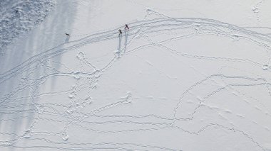 Karda ayak izleri var. Üst dron görüntüsü. Kış doğası. Kayak yapan insanlar.