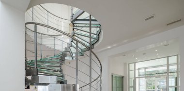 Lüks özel evin modern iç mimarisi. Camdan ve metalden yapılmış sarmal merdiven.