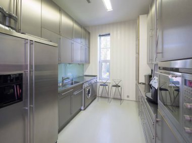 Lüks apartmandaki metal mutfağın modern iç mekanı. Ev aletleri. Çamaşır makinesi..