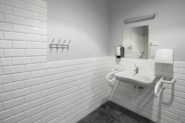 The interior of bathroom with facilities for the disabled. White bricks. Grey tile. clipart