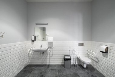 The interior of bathroom with facilities for the disabled. White bricks. Grey tile. clipart
