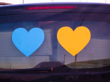 Arabanın arka camında onluk var. Mavi ve sarı kalpler. Ukrayna 'ya Destek.