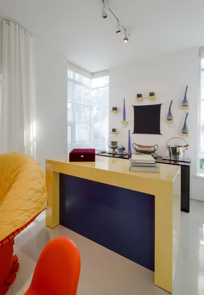 Modern interior of luxury apartment. White walls. Yelow, orange chairs. Books on table.