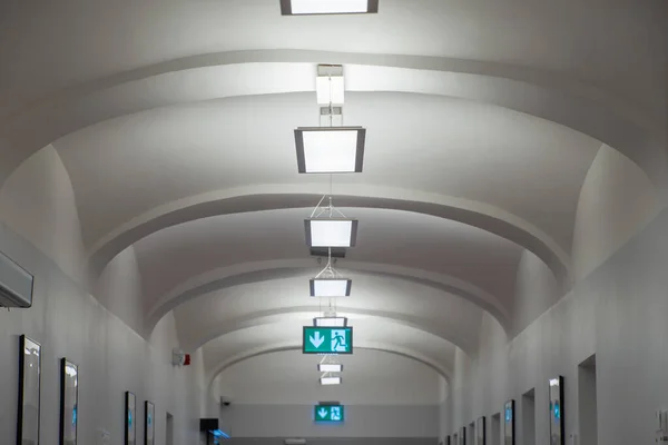 White ceiling in the corridor with glowing exit signs.