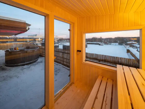 Interior of small wooden finnish sauna with glass door. Luxury private house.