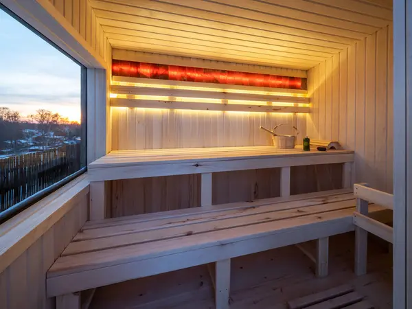 Interior of small wooden finnish sauna with window. Luxury private house.