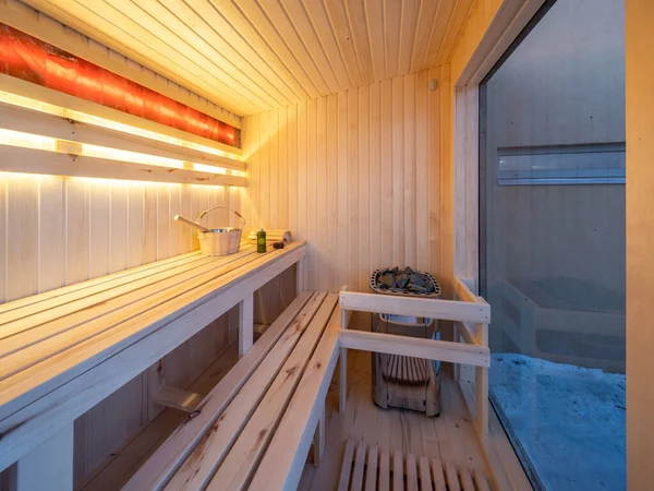 Interior of small wooden finnish sauna with window. Luxury private house.