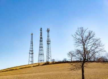 Telekomünikasyon kuleleri devrede. Kablosuz İletişim Anten Vericisi. Arka planda mavi gökyüzü. Ağaç.