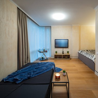 Dinlenme odası olan modern bir yatak odası. Duvarda televizyon var. Güneş yatakları.