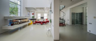 Lüks özel evin modern iç mimarisi. Geniş oturma odası. Beyaz duvarlar. Kırmızı kanepe. Spiral merdiven.