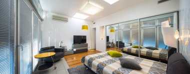 Lüks bir dairede, aydınlık yatak odasının modern iç mekanı. Ayna kapılı gardırop. Sıcak yatak. TV.