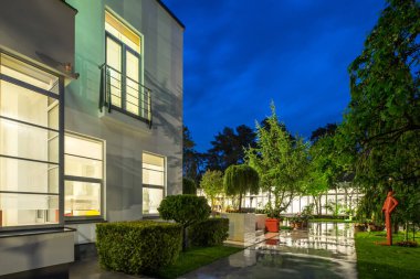 Lüks özel evin modern dış cephesi. Yazın alacakaranlıkta aydınlatılmış kır evi.