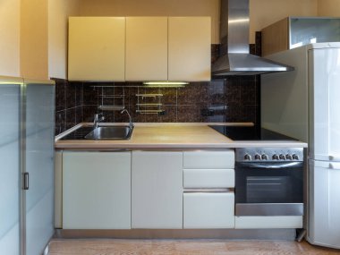 Dairenin içinde modern basit bir mutfak var. Lavabo, fırın ve buzdolabı..
