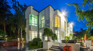 Lüks özel evin modern dış cephesi. Yazın alacakaranlıkta aydınlatılmış kır evi.