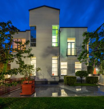 Lüks özel evin modern dış cephesi. Yazın alacakaranlıkta aydınlatılmış kır evi.