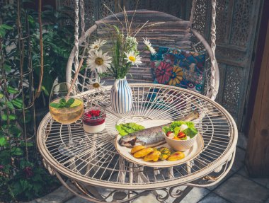 Balık, fırında patates ve tabakta taze salata. Lezzetli bir içki. Yakın plan.