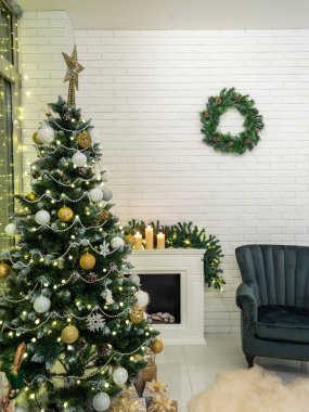 Noel ağacı, hediyeler. Madalyalı şömine. Duvarda çelenk var. İç mekan.