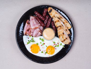 İngiliz kahvaltısı. Pastırma, yumurta, sosis, sos, kızarmış ekmek..