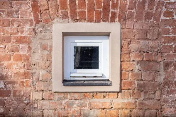 A small square window in an old brick wall.