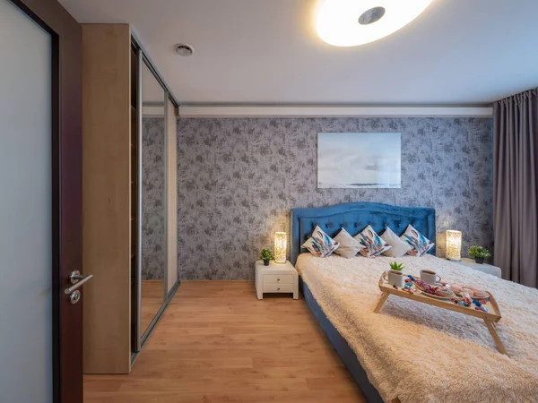 高級アパートのベッドルームのモダンなインテリア ナイター居心地の良いベッド 木製のトレイで朝食 — ストック写真