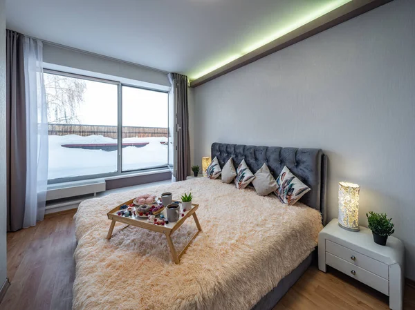 豪华公寓卧室的现代室内装饰 睡在舒适的床上 在木制托盘上吃早餐 窗外的雪 — 图库照片