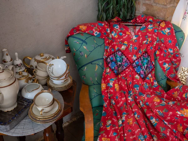 Robe Rouge Vintage Sur Fauteuil Tasses Assiettes Porcelaine Table Bois — Photo