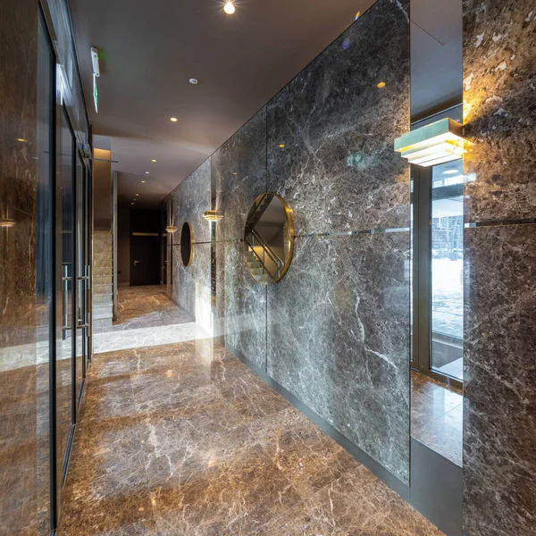 Modern interior of entrance hall in luxury residential apartment complex. Marble floor. Mirror on wall.