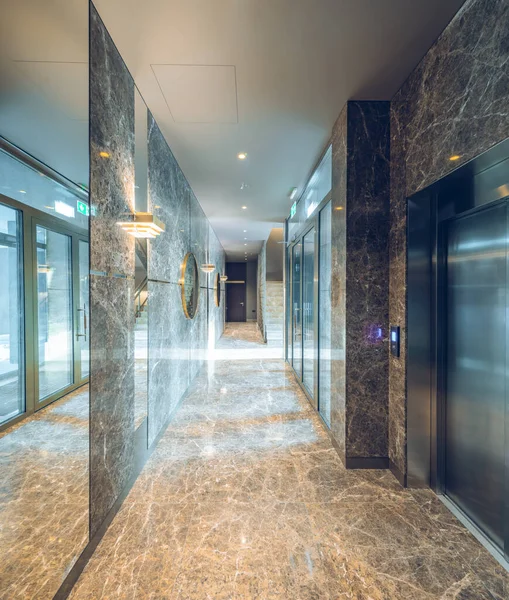 Modern interior of entrance hall in luxury residential apartment complex. Marble floor and walls. Elevator.