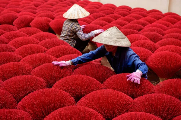 stock image Asian woman in a traditional ao dai dress working for drying  bundles of Incense sticks at Hanoi, Vietnam.