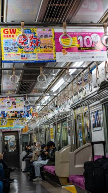 Japonya, Nisan 2024: Çevredeki yolcuların çatıdan sarkan renkli reklam tabelaları, Japonya.