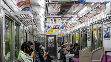 Japonya, Nisan 2024: Çevredeki yolcuların çatıdan sarkan renkli reklam tabelaları, Japonya.