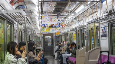 Japonya, Nisan 2024: Çevredeki yolcuların çatıdan sarkan renkli reklam tabelaları, Japonya.