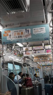 Japonya, Nisan 2024: Çevredeki yolcuların çatıdan sarkan renkli reklam tabelaları, Japonya.