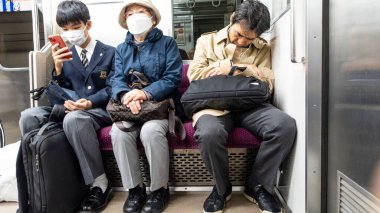 Japonya, Nisan 2024: Tokyo, Japonya 'da JR metrosunda oturan üç nesil. Demiryolları Japonya 'da en önemli yolcu taşımacılığıdır..