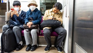 Japonya, Nisan 2024: Tokyo, Japonya 'da JR metrosunda oturan üç nesil. Demiryolları Japonya 'da en önemli yolcu taşımacılığıdır..