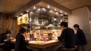 Japonya, Nisan 2024: İnsanlar Tokyo 'nun Shinjuku ilçesindeki küçük geleneksel Japon restoranında yemek yiyorlar