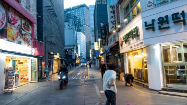 GÜNEY KORE, SEOUL Nisan 2024: Myeong-dong bölgesinin modern tarafında yürüyen büyük beyaz şapkalı kadın, Seul, Güney Kore