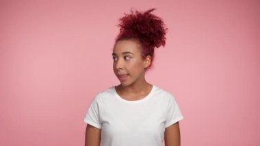 Kızıl saçlı Afro-Amerikan bir kadının etrafına bakması işaret parmağını dudaklarına koyması, sessizliğin gizli kalmasını sağlıyor. Beyaz tişörtlü Afrikalı kadın fotokopi alanı olan izole edilmiş pembe arka planda duruyor.