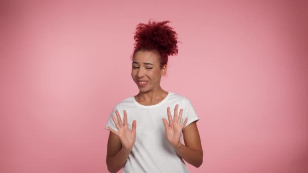 ポートレートアフリカ系アメリカ人の赤毛の巻き女性は カメラを見て停止手ジェスチャーを示す距離を必要としません 女性で白いTシャツ表現方法はありません いいえ感謝または私はそれがピンクの背景に署名する必要はありません — ストック動画
