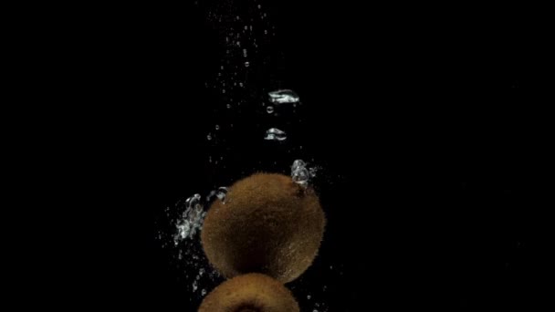 黒の背景に透明な水に落ちるスローモーション3キウイ 水族館で新鮮な果物が飛び散る 健康食品 — ストック動画